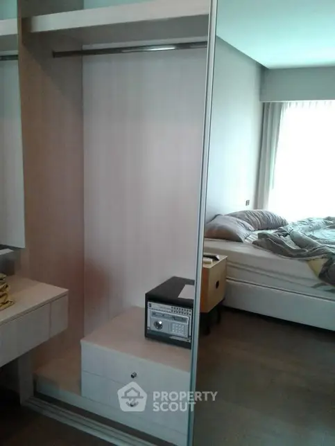 Modern bedroom with built-in wardrobe and safe, featuring natural light and cozy bedding.