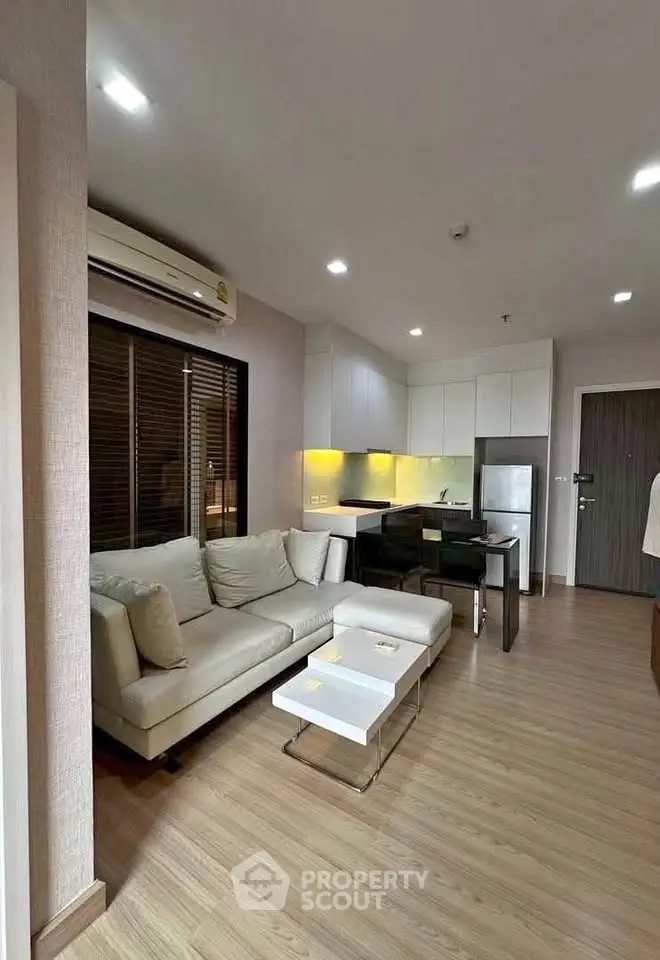 Modern open-plan living room with sleek kitchen and cozy seating area, perfect for urban living.