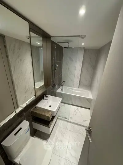Modern bathroom with marble tiles, glass shower, and sleek fixtures.