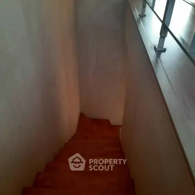 Modern staircase with wooden steps and sleek railing in contemporary home.