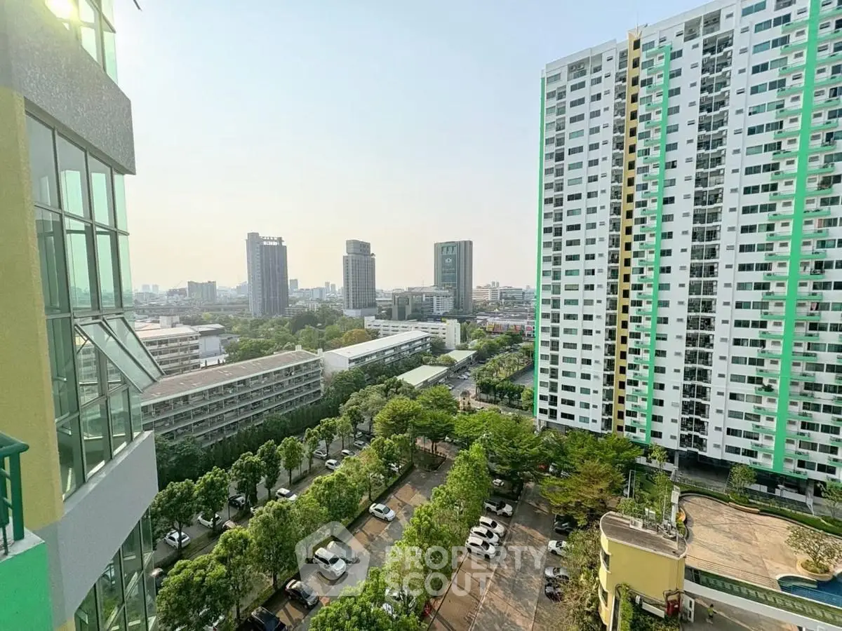 Stunning cityscape view from high-rise apartment balcony with lush greenery and modern buildings.