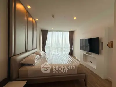Luxurious bedroom with large window and modern TV setup in high-rise apartment.
