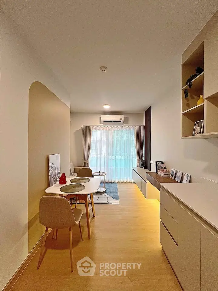 Modern living room with stylish decor and natural light, featuring a cozy dining area and elegant shelving.
