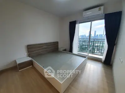 Spacious bedroom with city view and modern furnishings in high-rise apartment.