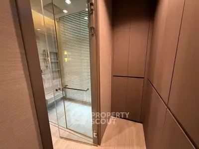 Luxurious modern bathroom with glass shower enclosure and elegant wood paneling.