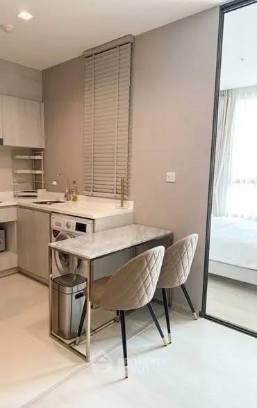 Modern kitchen with integrated washing machine and dining area in a stylish apartment.