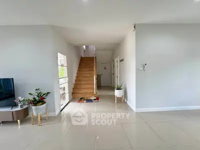 Spacious modern living area with sleek tile flooring and wooden staircase, perfect for family gatherings.