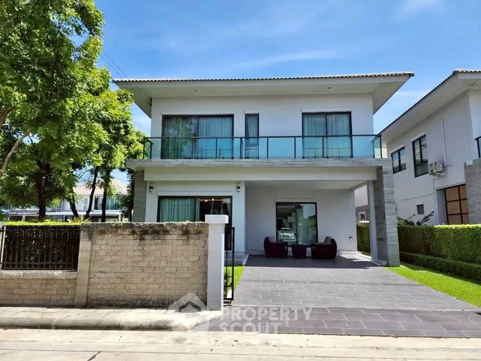 Modern two-story house with spacious balcony and lush greenery in a serene neighborhood.