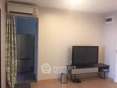 Modern living room with TV and air conditioning, adjacent to kitchen area.