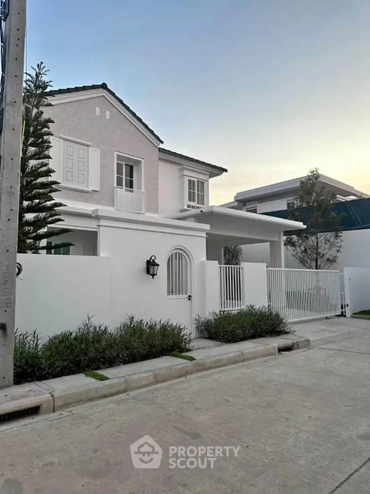 Charming two-story white house with modern design and lush greenery in a serene neighborhood.