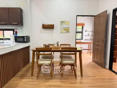 Modern dining area with wooden furniture and open kitchen layout, featuring sleek cabinetry and stylish decor.