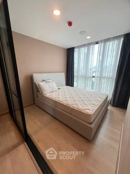 Modern bedroom with large window and stylish decor in a high-rise apartment.
