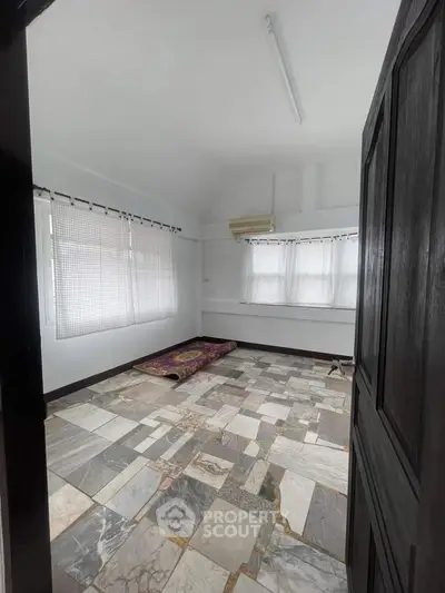 Spacious room with unique tiled flooring and large windows, perfect for customization.