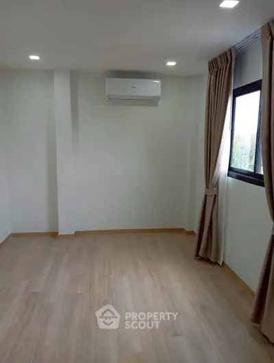 Spacious empty room with wooden flooring and air conditioning, perfect for customization.