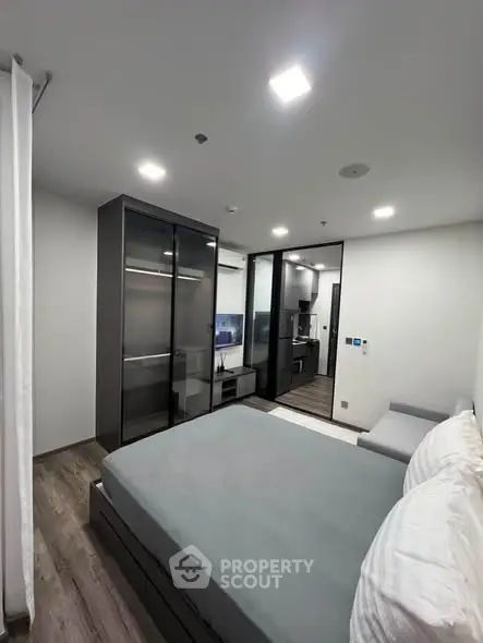 Modern bedroom with sleek design and glass wardrobe in a contemporary apartment.