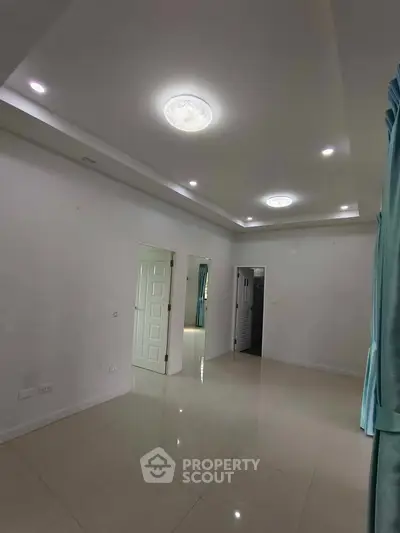 Spacious modern living room with glossy tiled floors and recessed lighting.