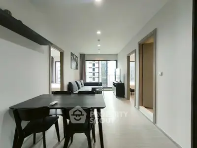 Modern open-plan living room with dining area and large windows in a stylish apartment.
