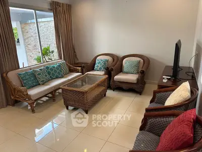 Charming living room with elegant wicker furniture and large window view.