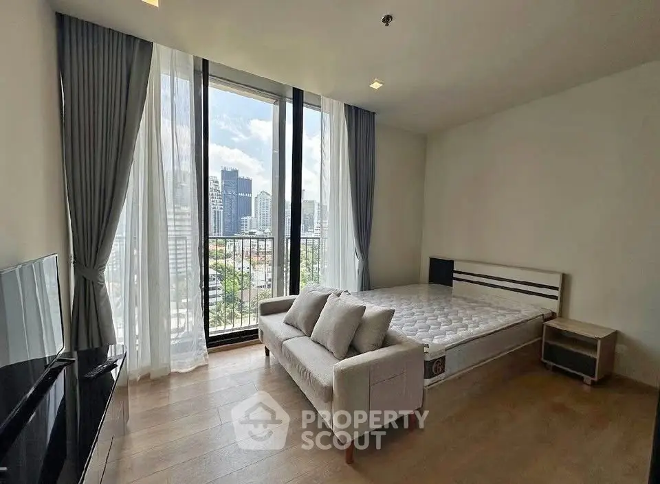Spacious bedroom with large windows offering stunning city views, modern furnishings, and natural light.