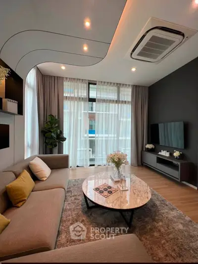 Modern living room with stylish decor, large windows, and cozy seating area.