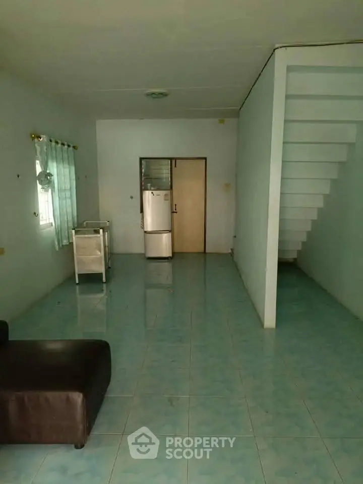 Spacious living area with tiled flooring and modern staircase, ideal for customization.