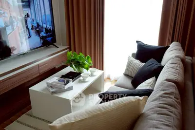 Cozy living room with modern decor, large TV, and natural light through curtains.