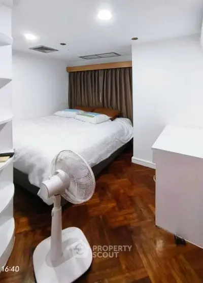 Cozy bedroom with wooden flooring and a fan, perfect for restful nights.