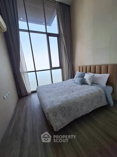 Luxurious bedroom with floor-to-ceiling windows offering stunning views, elegant decor, and ample natural light.