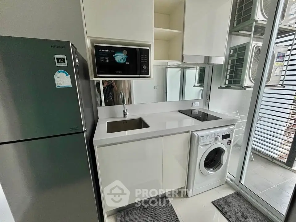 Modern kitchen with sleek appliances and washing machine in compact layout