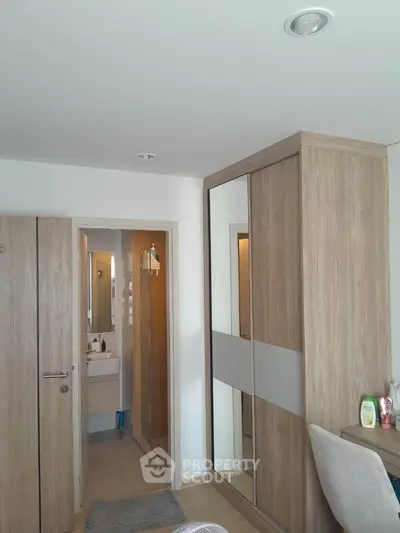 Modern bedroom with wooden wardrobe and view into bathroom