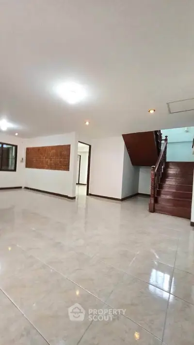 Spacious living room with elegant staircase and tiled flooring in a modern home.