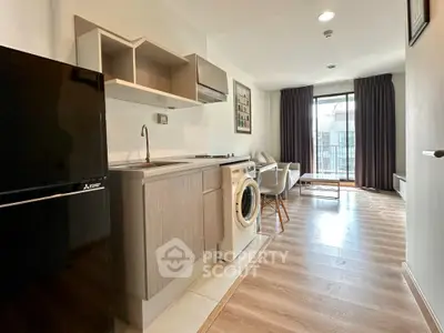 Modern studio apartment with open kitchen and washing machine, featuring bright natural light and stylish decor.