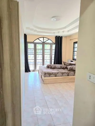 Spacious bedroom with large windows and elegant ceiling design
