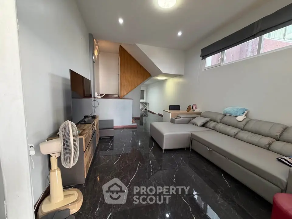 Spacious modern living room with sleek black flooring and stylish furniture, perfect for relaxation and entertainment.