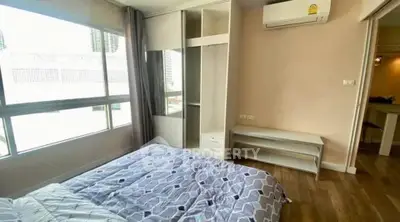 Spacious bedroom with large windows and modern furnishings in a city apartment.