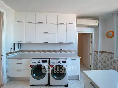 Modern kitchen with washing machines and sleek white cabinetry