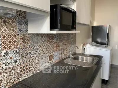 Modern kitchen with stylish patterned backsplash, sleek black countertop, and built-in appliances.