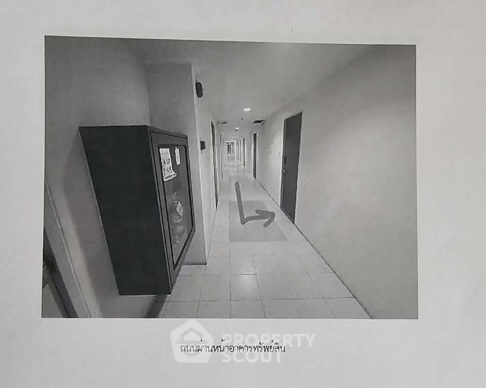 Monochrome hallway in a residential building with directional arrow on floor.