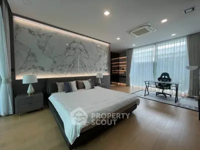 Luxurious modern bedroom with marble accent wall and stylish workspace