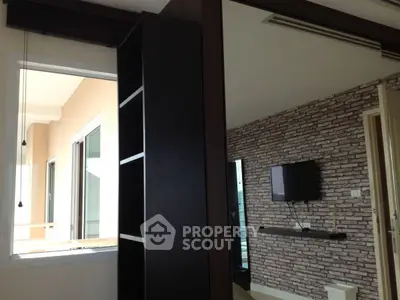 Modern bedroom with brick accent wall and large mirror reflecting natural light.