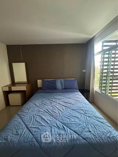 Cozy bedroom with large window and modern decor, perfect for relaxation and comfort.