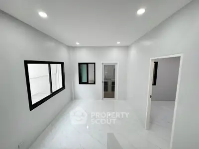 Spacious modern room with sleek white flooring and large windows for natural light.