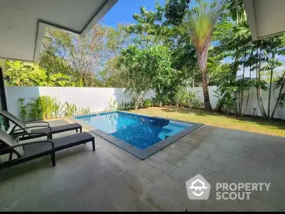 Luxurious private pool with lush garden in serene outdoor setting.