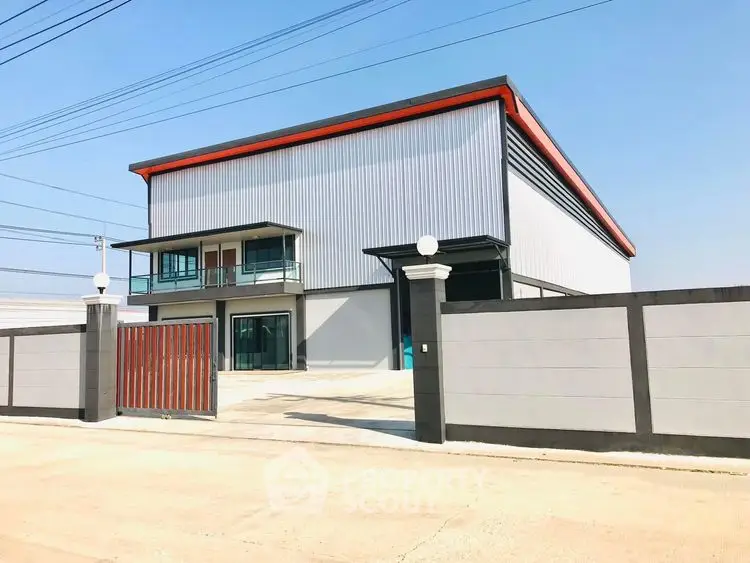 Modern industrial warehouse with spacious exterior and secure gated entrance.