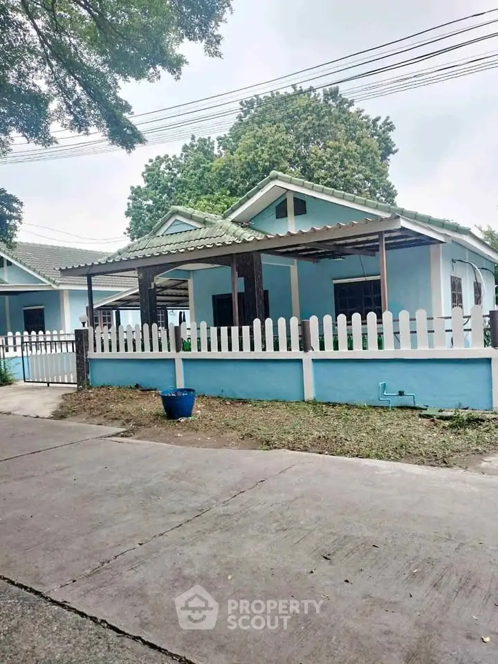 Charming blue house with white picket fence and lush greenery