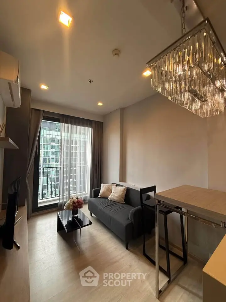 Modern living room with elegant chandelier and city view, featuring cozy sofa and stylish decor.