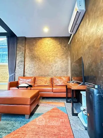 Modern living room with leather sofa and air conditioning, featuring stylish decor and natural light.