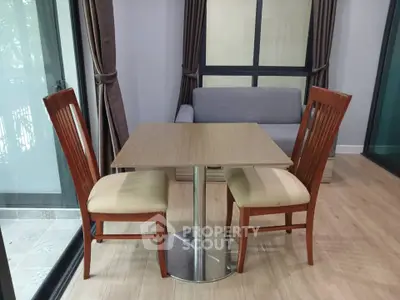 Cozy dining area with wooden table and chairs, adjacent to a modern living room.