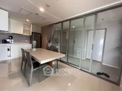 Modern kitchen with sleek dining area and glass partition in stylish apartment.