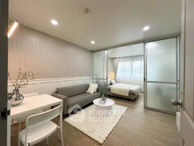 Modern studio apartment with cozy living area and bedroom separated by glass partition.